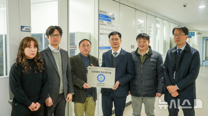 [창원=뉴시스]한국전기연구원(KERI) 김남균 원장(왼쪽서 네 번째)이 절연재료화학실험실 이대호 박사와 '안전관리 우수연구실 인증 현판'을 들고 기념사진을 찍고 있다. 절연재료화학실험실은 이번에 우수연구실 중 '최우수 연구실'에도 선정됐다.(사진=한국전기연구원 제공) 2026.01.19. photo@newsis.com