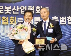 [창원=뉴시스]20일 오후 창원 그랜드머큐어앰배서더 호텔에서 열린 '2026년 경남로봇산업협회 정기총회 및 회장 이·취임식'에서 남창현(오른쪽) 취임회장이 정영화 이임회장에게 감사패와 꽃다발을 전달하고 있다.(사진=경남로봇산업협회 제공) 2026.01.20. photo@newsis.com