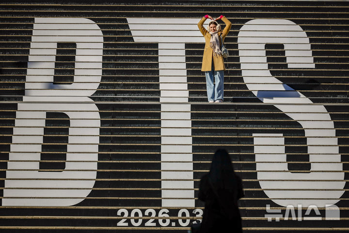 [서울=뉴시스] 정병혁 기자 = 20일 서울 종로구 세종문화회관 계단을 찾은 외국인 여행객들이 방탄소년단(BTS) 래핑을 배경으로 사진을 찍고 있다. 2026.01.20. jhope@newsis.com