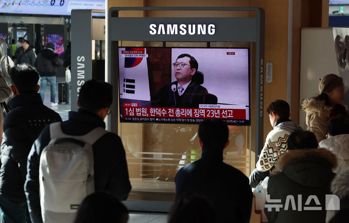 [서울=뉴시스] 조성우 기자 = 한덕수 전 국무총리의 내란 우두머리 방조, 내란 중요임무 종사 혐의 사건 1심 선고 재판이 열린 21일 오후 서울역 대합실에서 시민들이 한 전 총리의 1심 징역 23년 선고 관련 뉴스를 시청하고 있다. 2026.01.21. xconfind@newsis.com