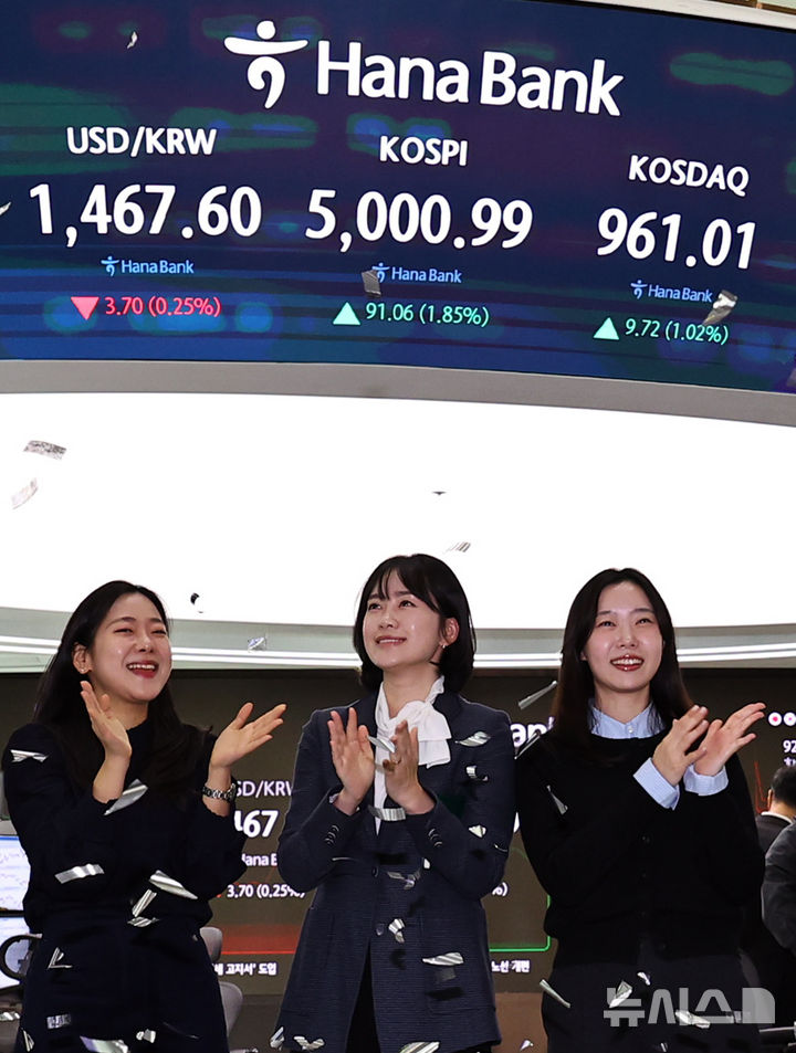 [서울=뉴시스] 최진석 기자 = 코스피가 꿈의 숫자로 여겨지던 '오천피'에 도달하며 코스피 5000 시대가 열린 22일 오전 서울 중구 하나은행 딜링룸에서 관계자들이 코스피 5000 돌파를 축하하고 있다. 코스피는 전 거래일(4909.93)보다 77.13포인트(1.57%) 상승한 4987.06에 개장했다.2026.01.22. myjs@newsis.com