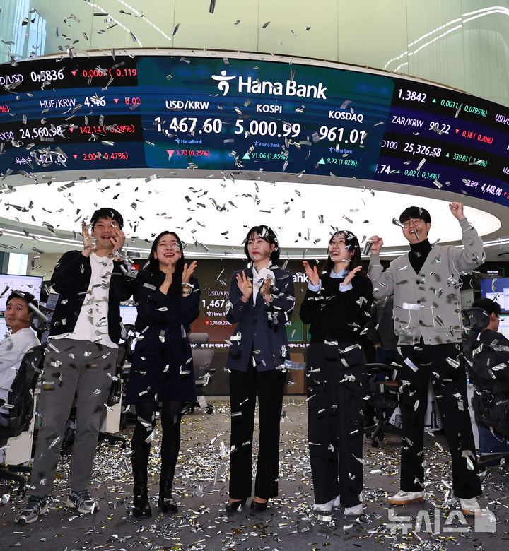 [서울=뉴시스] 최진석 기자 = 코스피가 꿈의 숫자로 여겨지던 '오천피'에 도달하며 코스피 5000 시대가 열린 22일 오전 서울 중구 하나은행 딜링룸에서 관계자들이 코스피 5000 돌파를 축하하고 있다. 코스피는 전 거래일(4909.93)보다 77.13포인트(1.57%) 상승한 4987.06에 개장했다.2026.01.22. myjs@newsis.com