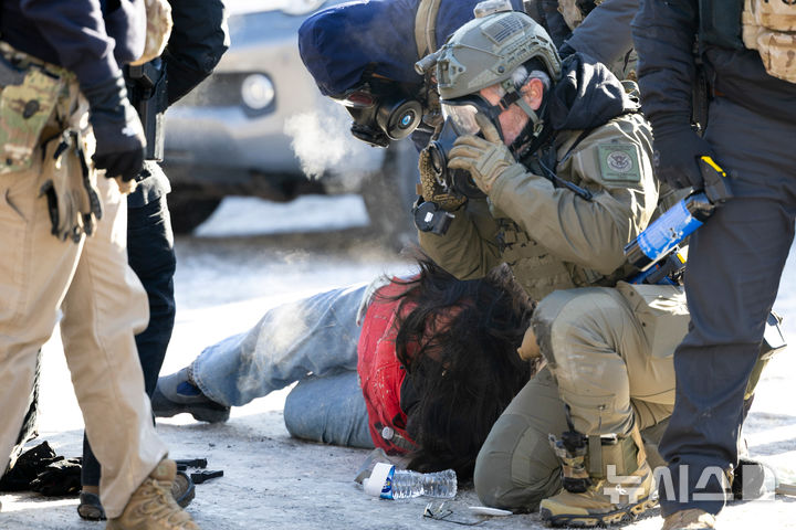 [AP/뉴시스] 24일 미니애폴리스 시위대원이 연방 이민요원에 땅바닥에 쓰려트려져 붙잡히고 있다. 