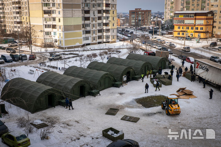 [AP/뉴시스] 25일 키이우 긴급복구 요원들이 아직 전기가 들어오지 않아 난방이 안 되는 아파트 주민용 임시 텐트를 치고 있다