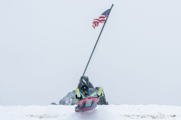 [알링턴=AP/뉴시스] 25일(현지 시간) 미 버지니아주 알링턴에 눈이 내리는 가운데 한 소년이 미 해병대 전쟁 기념비 앞에서 눈썰매를 타고 있다. 강력한 눈 폭풍이 미 남부에서 북동부로 이동하면서 폭설과 결빙으로 인한 대규모 정전 사태와 항공편 결항 등 피해가 속출하고 있다. 2026.01.26.