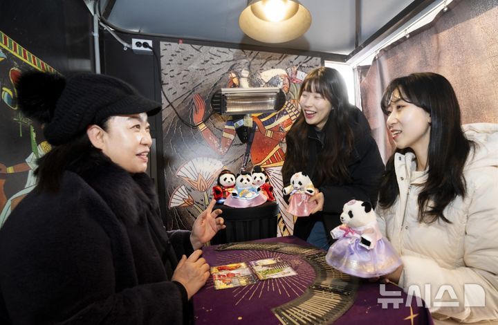 [용인=뉴시스]에버랜드 타로점에서 모델들이 신년 바오패밀리 굿즈와 함께 타로를 체험하고 있다.(사진=에버랜드 제공)2026.01.26.photo@newsis.com