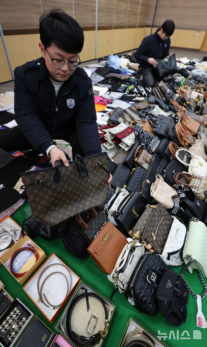 [인천=뉴시스] 전진환 기자 = 27일 오전 인천 중구 관세청 인천본부세관에서 세관 직원들이 위조 명품 온라인 쇼핑몰 운영조직으로부터 압수한 위조 상품을 정리하고 있다.&nbsp; 인천본부세관은 온라인 쇼핑몰을 운영하며, 정품시가 1,200억 원 상당의 가방, 의류, 신발 등 위조 상품 7만 7천여점을 국내로 유통하고 범죄수익 165억 원을 타인 명의로 은닉·세탁한 총책 A씨를 관세법·상표법·범죄수익은닉규제법 위반 혐의로 인천지방검찰청에 구속 송치하고, 관련자 3명은 공모 혐의로 불구속 송치했다고 밝혔다. 2026.01.27. amin2@newsis.com