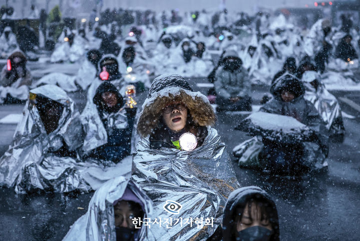[서울=뉴시스] 뉴시스 정병혁 기자가 2일 한국사진기자협회 제62회 한국보도사진전에서 '폭설 속 대통령 퇴진 외치는 키세스 시위대'로 대상을 수상했다.사진은 지난 2025년 1월 5일 서울 용산구 대통령 관저 인근에서 열린 1박 2일 민주노총 철야투쟁에서 시민들이 눈을 맞으며 은박 비닐을 덮은 채 자리를 지키고 있다. (사진=한국사진기자협회 제공) 2026.02.02. photo@newsis.com *재판매 및 DB 금지