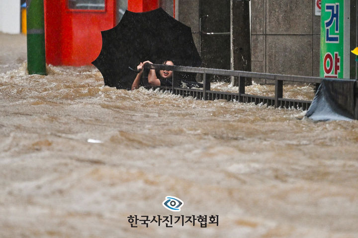 [서울=뉴시스] 뉴시스 이영주 기자가 2일 한국사진기자협회 제62회 한국보도사진전 뉴스 부문에서 '426㎜ 괴물 폭우 속 절체절명 시민'으로 우수상을 수상했다.사진은 지난 2025년 7월 17일 광주지역에 하루 최고 폭우가 쏟아져 침수된 광주 북구청 앞 도로에서 한 시민이 물살에 휩쓸리고 있다. (사진=한국사진기자협회 제공) 2026.02.02. photo@newsis.com *재판매 및 DB 금지