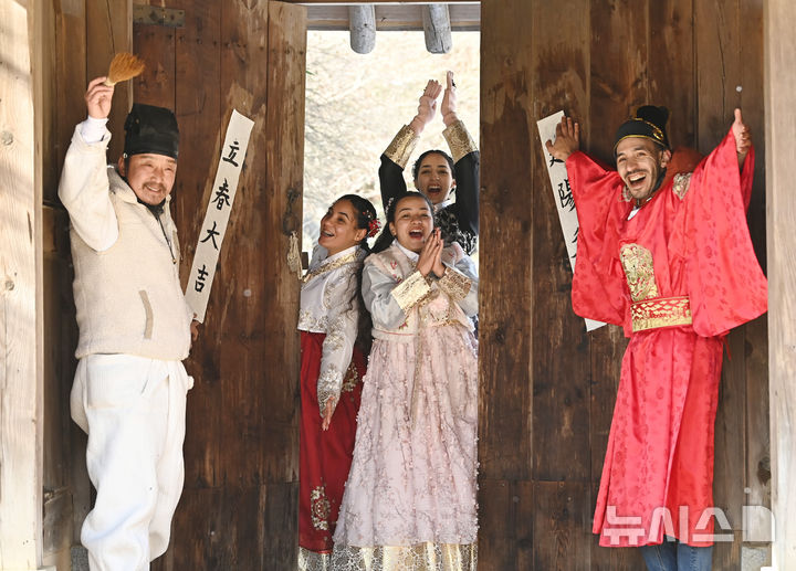 [용인=뉴시스] 김종택 기자 = 절기상 입춘을 이틀 앞둔 2일 경기 용인시 한국민속촌에서 외국인 관광객들이 입춘첩을 대문에 붙이고 있다.&nbsp; '입춘대길 건양다경(立春大吉 建陽多慶)'은 '봄이 시작되니 크게 길하고 경사스러운 일이 많이 생기길 기원한다'는 의미를 갖고 있다. 2026.02.02. jtk@newsis.com