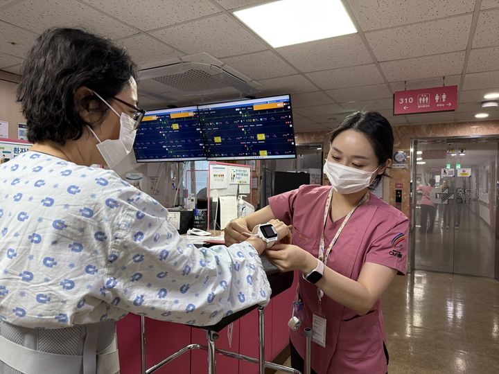 [서울=뉴시스] 간호사가 환자에게 스마트 병상 모니터링 시스템 씽크와 연동되는 웨어러블 기기를 착용시키고 있다. (사진=대웅제약 제공) 2026.02.04. photo@newsis.com *재판매 및 DB 금지