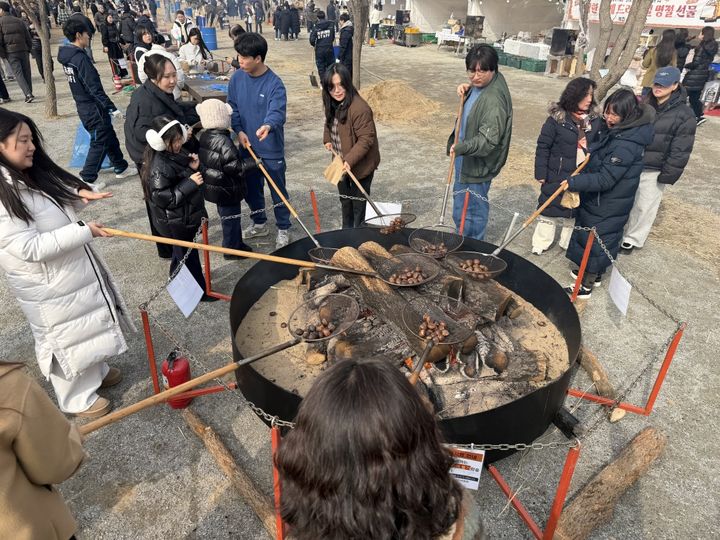 [공주=뉴시스] 대형 화로 앞에서 군밤 굽는 관람객들.(사진= 공주시).2026.02.04.photo@newsis.com. *재판매 및 DB 금지