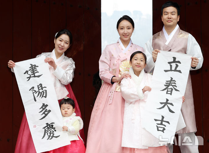 [서울=뉴시스] 조성우 기자 = 절기상 입춘인 4일 오전 서울 중구 남산골한옥마을에서 열린 입춘첩 붙이기 시연 행사에 참여한 1990년생 경오년 말띠인 박민지(왼쪽) 씨와 박은혜 씨가 가족과 함께 '입춘대길·건양다경'이라고 적힌 입춘첩을 들고 포즈를 취하고 있다. 2026.02.04. xconfind@newsis.com