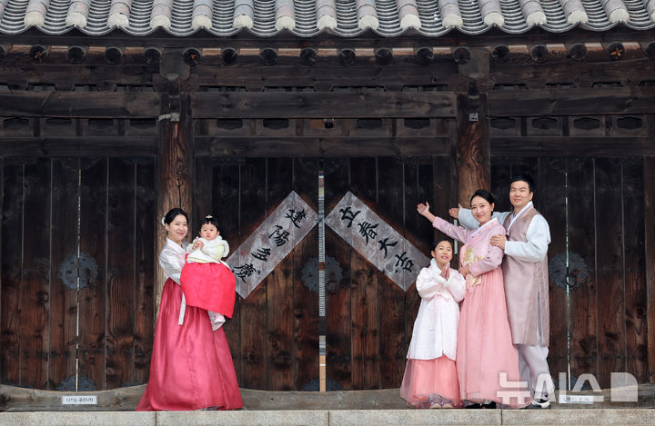 [서울=뉴시스] 조성우 기자 = 절기상 입춘인 4일 오전 서울 중구 남산골한옥마을에서 열린 입춘첩 붙이기 시연 행사에 참여한 1990년생 경오년 말띠인 박민지(왼쪽) 씨와 박은혜 씨가 가족과 함께 '입춘대길·건양다경'이라고 적힌 입춘첩을 붙인 뒤 포즈를 취하고 있다. 2026.02.04. xconfind@newsis.com