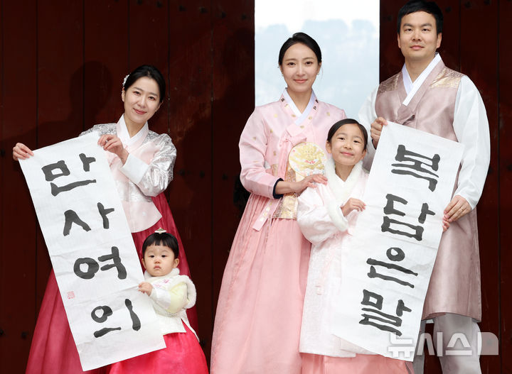 [서울=뉴시스] 조성우 기자 = 절기상 입춘인 4일 오전 서울 중구 남산골한옥마을에서 열린 입춘첩 붙이기 시연 행사에 참여한 1990년생 경오년 말띠인 박민지(왼쪽) 씨와 박은혜 씨가 가족과 함께 '복담은말·만사여의'이라고 적힌 입춘첩을 들고 포즈를 취하고 있다. 2026.02.04. xconfind@newsis.com