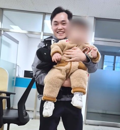 [뉴시스]경찰의 응급 후송을 받은 1살 아기가 경찰관의 품에 안겨있다. (사진 = 경찰청 유튜브 캡처) *재판매 및 DB 금지