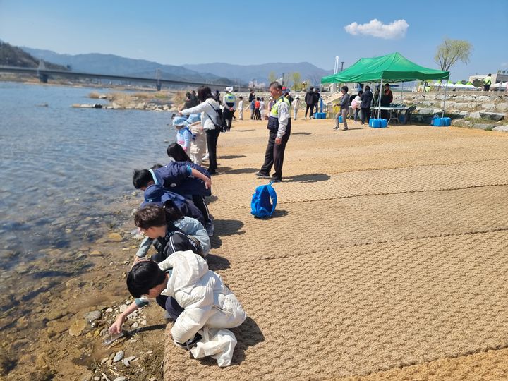 [부산=뉴시스] 아이들이 어린 연어를 방류하고 있다. (사진=한국수산자원공단 제공) 2026.02.06. photo@newsis.com *재판매 및 DB 금지