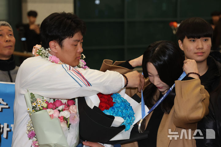 [인천공항=뉴시스] 권창회 기자 = 2026 밀라노-코르티나담페초 동계올림픽 스노보드 남자 평행대회에서 은메달을 차지한 김상겸이 10일 인천국제공항 제1여객터미널을 통해 귀국해 아내에게 은메달을 걸어주고 있다. 2026.02.10. kch0523@newsis.com