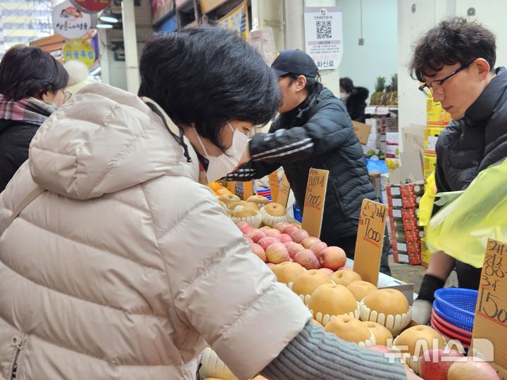 [안양=뉴시스] 박석희기자=과일 가계를 찾은 한 손님이 비싼 가격에 쉽게 고르지 못하고 있다. 2026.02.14.phe@newsis.com