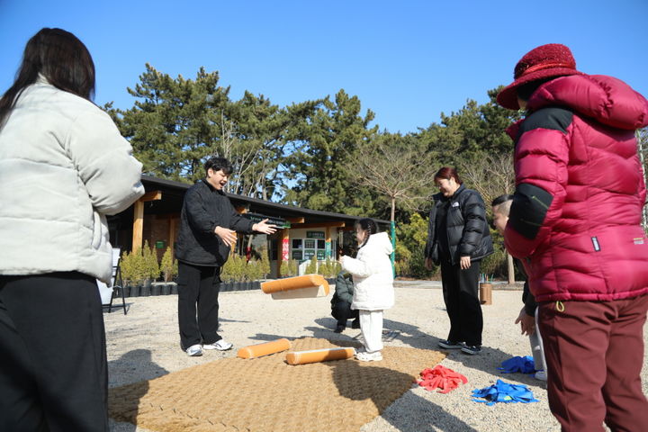 [태안=뉴시스] 지난해 설 연휴 기간 천리포수목원을 찾은 한 가족 탐방객이 입구 정원에 마련된 전통놀이 공간에서 윷놀이를 하고 있다. (사진=천리포수목원 제공) 2026.02.15. photo@newsis.com *재판매 및 DB 금지