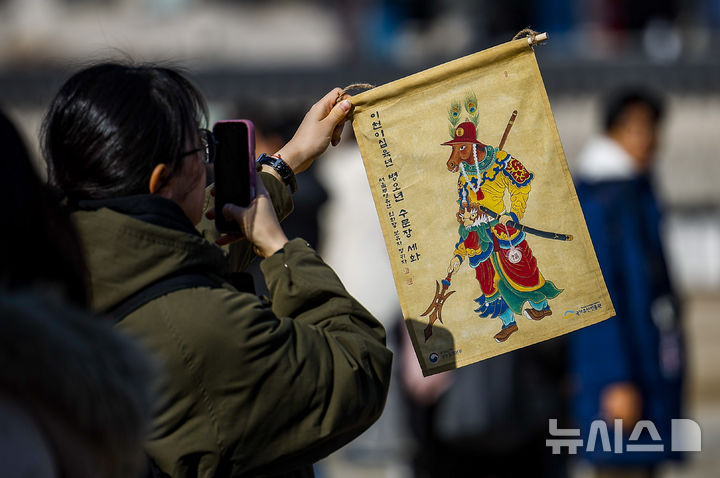 [서울=뉴시스] 정병혁 기자 = 16일 서울 종로구 경복궁 흥례문 광장에서 열린 2026년 병오년 수문장 세화 나눔행사에서 시민들이 세화를 받은 뒤 사진을 찍고 있다. 2026.02.16. jhope@newsis.com