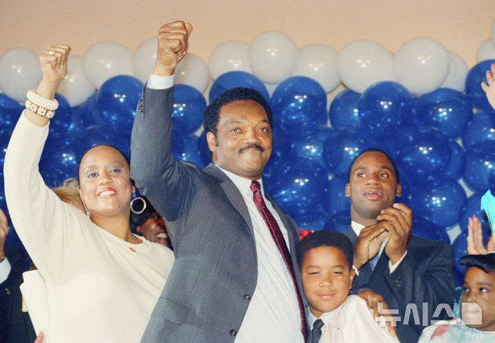 [로스앤젤레스=AP/뉴시스] 제스 잭슨 목사가 1988년 6월 8일 캘리포니아주 로스앤젤레스 힐튼 호텔에서 마이클 듀카키스에게 대선 예비경선에서 패배한 뒤 자녀들과 함께 참석해 손을 번쩍 들고 있다. 2026.02.17.