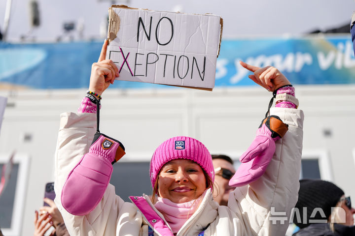 [테세로=AP/뉴시스] 미국의 노르딕복합 선수 아니카 말라친스키가 17일(현지 시간) 이탈리아 테세로 크로스컨트리 스키 스타디움에서 열린 2026 밀라노·코르티나담페초 동계올림픽 노르딕복합 개인 군데르센 라지힐(10㎞) 경기장을 찾아 여성 노르딕복합 선수의 올림픽 출전 허가를 요구하는 팻말을 들고 있다. 2026.02.18.