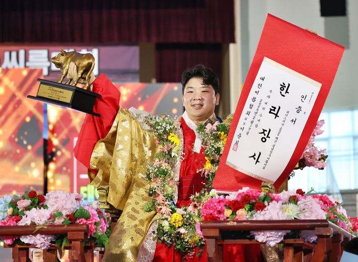 [서울=뉴시스] 17일 충청남도 태안군 태안종합실내체육관에서 열린 '위더스제약 2026 태안설날장사씨름대회' 한라장사(105㎏ 이하)에 등극한 김무호(울주군청)가 장사꽃가마를 타고 장사인증서와 황소트로피를 들고 기념사진을 찍고 있다. (사진=대한씨름협회 제공) 2026.02.17. photo@newsis.com *재판매 및 DB 금지