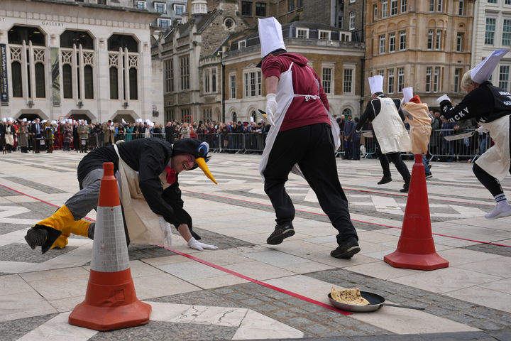 [런던=AP/뉴시스] 17일(현지 시간) 영국 런던 길드홀에서 열린 전통 '팬케이크' 경주에서 한 참가자가 팬케이크를 들고 달리다 넘어지고 있다. 이 대회 참가자들은 프라이팬에 팬케이크를 올린 채 일정 구간을 달리면서 최소 1번은 공중에서 팬케이크를 뒤집어야 한다. 2026.02.18. *재판매 및 DB 금지