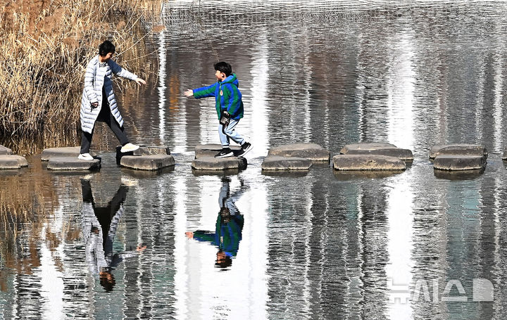 [수원=뉴시스] 김종택 기자 = 절기상 우수인 19일 경기 수원시 팔달구 서호천을 찾은 시민들이 온화한 날씨속에 산책하며 징검다리를 건너고 있다. 2026.02.19. jtk@newsis.com