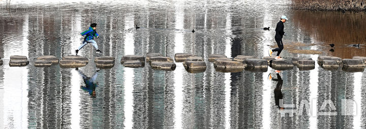 [수원=뉴시스] 김종택 기자 = 절기상 우수인 19일 경기 수원시 팔달구 서호천을 찾은 시민들이 온화한 날씨속에 산책하며 징검다리를 건너고 있다. 2026.02.19. jtk@newsis.com