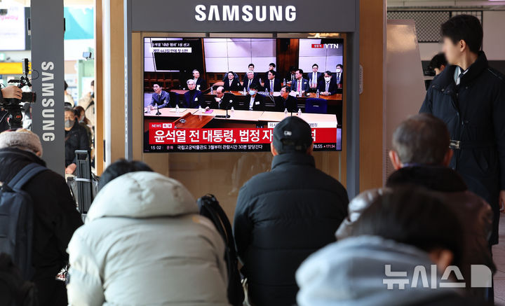 [서울=뉴시스] 이영환 기자 = 19일 오후 서울 용산구 서울역에서 시민들이 '내란 우두머리 혐의' 윤석열 전 대통령의 1심 선고 공판 중계를 시청하고 있다. 2026.02.19. 20hwan@newsis.com