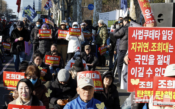 [서울=뉴시스] 김혜진 기자 = 윤석열 전 대통령의 내란 우두머리 혐의에 대한 1심 선고가 내려진 19일 서울중앙지법 인근에서 촛불행동 관계자들이 중계를 시청하고 있다. 2026.02.19. jini@newsis.com