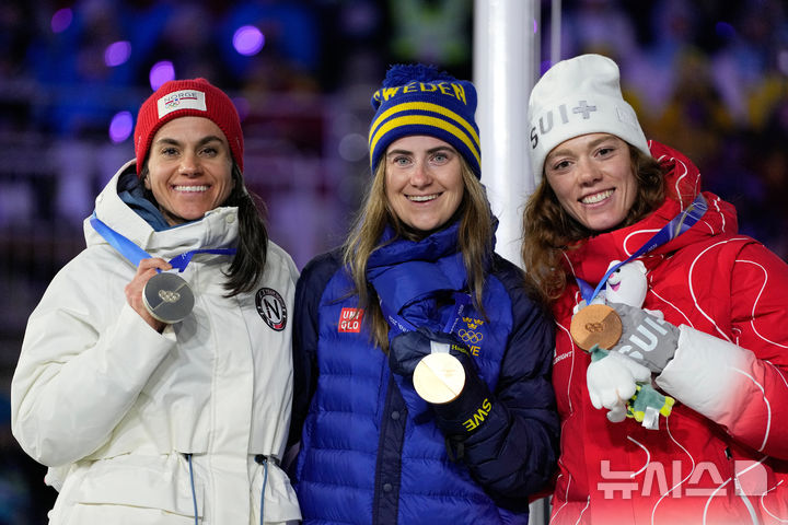 [베로나=AP/뉴시스] 2026 밀라노·코르티나담페초 동계올림픽 크로스컨트리 스키 여자 50㎞ 매스스타트 클래식 메달리스트 에바 안데르손(스웨덴·가운데), 하이디 벵(노르웨이·왼쪽), 나디아 켈린(스위스)이 23일(한국 시간) 이탈리아 베로나의 베로나 아레나에서 열린 대회 폐회식에서 메달을 받고 기뻐하고 있다. 2026.02.23.