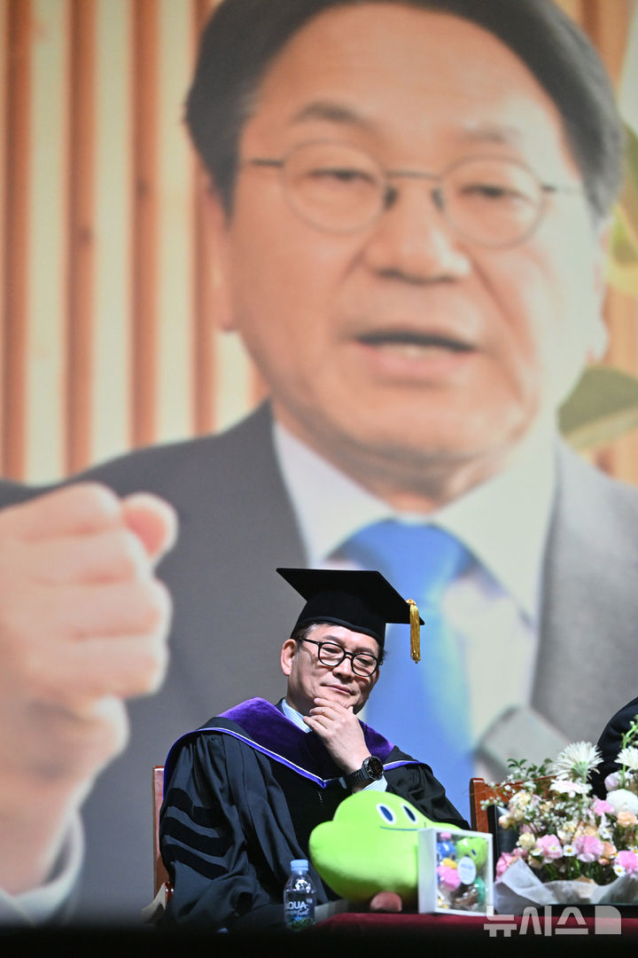 [광주=뉴시스] 이영주 기자 = 송영길 전 더불어민주당 당대표가 25일 오전 광주 동구 조선대학교 해오름관에서 열린 2025학년도 대학원 석·박사 학위수여식에 참여해 축사 순서를 기다리는 가운데 배경으로 강기정 광주시장의 영상 축사가 진행되고 있다. 송 전 대표와 강 시장은 광주 대동고 선후배 사이이자 같은 전남 고흥 출신이다. 2026.02.25. leeyj2t78@newsis.com