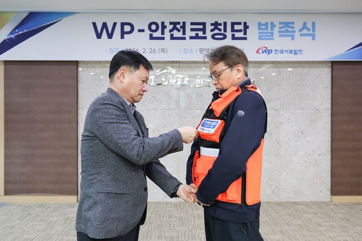 [세종=뉴시스] 한국서부발전은 26일 경기 평택발전본부에서 '더블유피(WP)·안전코칭단 발족식'을 개최했다. 사진은 이정복 서부발전 사장(왼쪽)이 현장 안전 파수꾼으로 위촉된 대표에게 안전조끼를 입혀주는 모습. (사진=서부발전 제공) 2026.02.26. photo@newsis.com *재판매 및 DB 금지