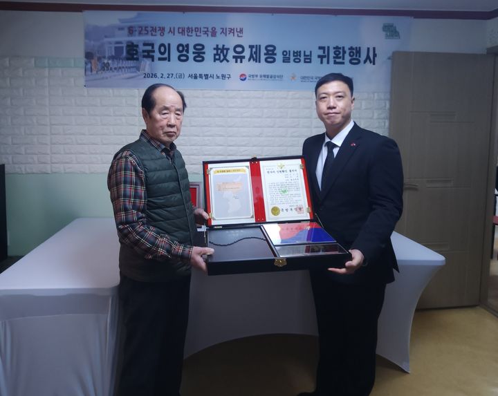 [서울=뉴시스] 2월 27일 서울시 노원구에 위치한 고 유제용 일병의 남동생 유제만 씨 자택에서 열린 호국의 영웅 귀환행사에서 김성환 국유단장 직무대리(오른쪽)와 유제만 씨(왼쪽)가 전사자 신원확인 통지서 등이 담긴 호국의 얼 함을 들고 기념사진을 촬영하고 있다. (사진=국방부 제공) 2026.02.27. photo@newsis.com *재판매 및 DB 금지