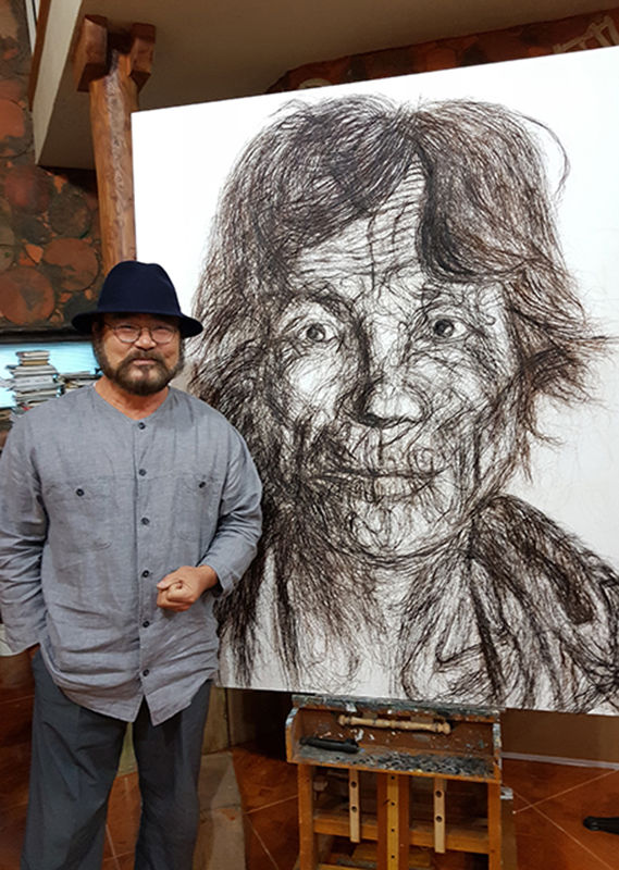 황재형 화백이 2017년 태백 화실에서 머리카락과 흑연을 활용한 독창적인 기법의 광부 작품 앞에서 포즈를 취하고 있는 모습.(사진=뉴시스) *재판매 및 DB 금지