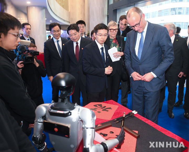 [항저우=신화/뉴시스] 중국을 공식방문 중인 프리드리히 메르츠 독일 총리가 26일 중국 동부 저장성 항저우에서 유니트리의 휴머노이드 로봇이 '행운'을 뜻하는 한자 '복(福)'을 쓰는 모습을 지켜보고 있다. 2025.02.27