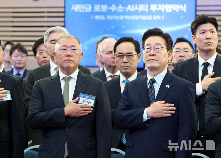 [군산=뉴시스] 최동준 기자 = 이재명 대통령이 27일 전북 군산 새만금컨벤션센터에서 열린 '새만금 로봇·수소·AI시티 투자협약식'에서 정의선 현대자동차그룹 회장 등 참석자들과 국민의례를 하고 있다. (청와대통신사진기자단) 2026.02.27. photocdj@newsis.com