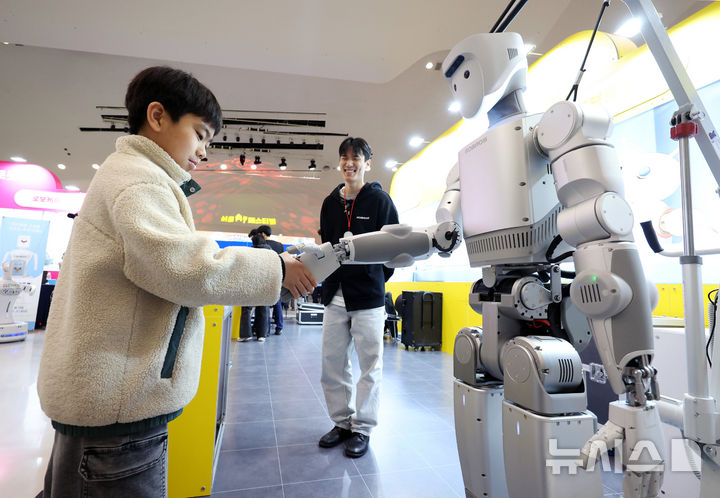 [서울=뉴시스] 김진아 기자 = 28일 서울 중구 동대문디자인플라자(DDP) 아트홀에서 열린 '서울AI페스티벌 2026'에서 한 어린이가 '로브로스'의 휴머노이드 로봇과 인사하고 있다. 이번 행사 주제는 '인공지능(A)이 내게 말을 걸었다 - 몸으로 느끼는 일상 속 Physical AI'다. 인공 지능이 소프트웨어를 넘어 로봇·디바이스·웨어러블 등 실체를 가진 '피지컬 AI(Physical AI)' 기술로 구현되는 모습을 직접 체험할 수 있다. 2026.02.28. bluesoda@newsis.com