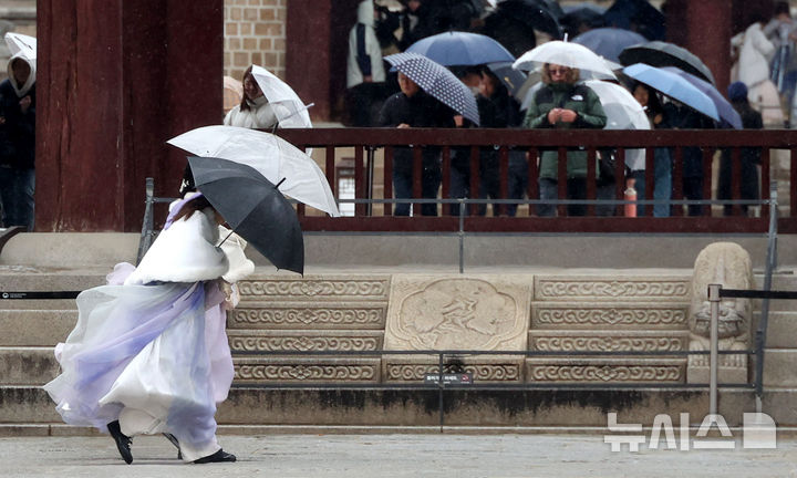 [서울=뉴시스] 추상철 기자 = 강풍을 동반한 비가 내린 2일 오전 서울 종로구 경복궁에서 외국인 관광객이 우산을 쓰고 발걸음을 재촉하고 있다. 2026.03.02. scchoo@newsis.com