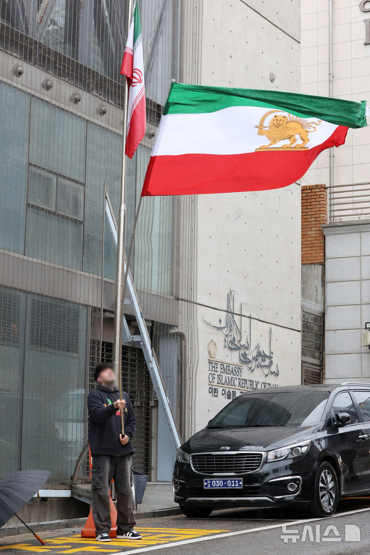 [서울=뉴시스] 조성우 기자 = 미국과 이스라엘의 이란 공습으로 아야톨라 알리 하메네이 최고지도자의 사망이 공식 확인된 가운데 2일 서울 용산구 주한 이란이슬람공화국 대사관 앞에서 한 이란인이 팔레비 왕조 시절 이란 국기를 흔들고 있다. 2026.03.20. xconfind@newsis.com.
