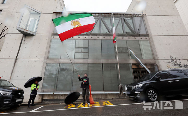 [서울=뉴시스] 조성우 기자 = 미국과 이스라엘의 이란 공습으로 아야톨라 알리 하메네이 최고지도자의 사망이 공식 확인된 가운데 2일 서울 용산구 주한 이란이슬람공화국 대사관 앞에서 한 이란인이 팔레비 왕조 시절 이란 국기를 흔들고 있다. 이란 정부는 지난 1일(현지 시간) 하메네이 최고지도자의 사망을 발표하며 40일간의 국가 애도 기간과 일주일간의 공휴일을 선포했다. 2026.03.02. xconfind@newsis.com