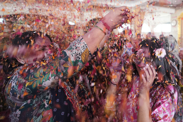 [아마다바드=AP/뉴시스] 3일(현지 시간) 인도 아마다바드 자간나트 사원에서 한 여성이 힌두교 색 축제 '홀리'(Holi)를 맞아 신자들에게 꽃잎을 뿌리고 있다. 2026.03.03.