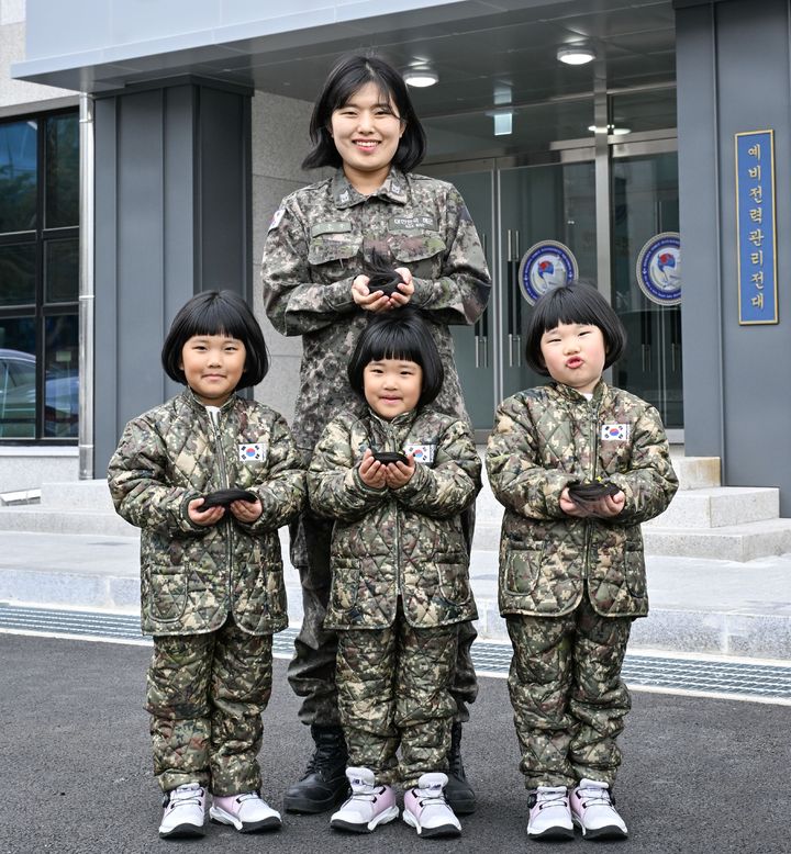 [서울=뉴시스] 해군 제8전투훈련단 소속 이은주 상사와 세쌍둥이 딸(왼쪽부터 장은진(첫째), 장소진(셋째), 장유진(둘째) 양)들이 지난달 26일 8전단 예하 예비전력관리전대 건물 앞에서 소아암 아동 돕기를 위해 자른 각 25cm 길이의 머리카락을 손에 들고 기념사진을 촬영하고 있다. (사진=해군 제공) 2026.03.05. photo@newsis.com *재판매 및 DB 금지