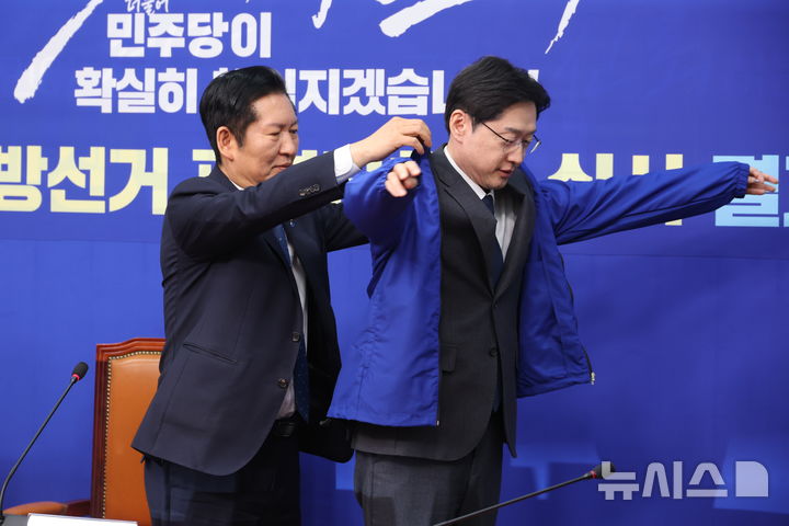 [서울=뉴시스] 조성봉 기자 = 정청래 더불어민주당 대표가 5일 오후 서울 여의도 국회에서 열린 중앙당공천관리위원회 공천 심사 발표에서 경남도지사 후보로 확정된 김경수 지방시대위원회 위원장에게 점퍼를 입혀주고 있다. 2026.03.05. suncho21@newsis.com