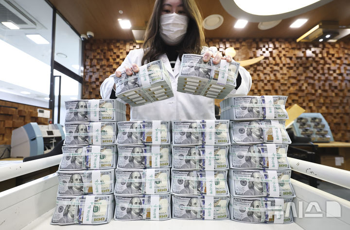 [서울=뉴시스] 28일(현지 시간) 월스트리트저널(WSJ)에 따르면 과거 시장 불안기에 주식의 하락분을 상쇄해주던 채권이 이번에는 제 역할을 하지 못하고 있다. 사진은 서울 중구 을지로 하나은행 본점 위변조센터에서 직원이 달러를 들어보이고 있다. 2026.03.29.