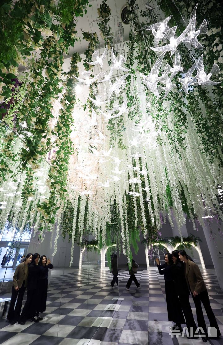 [부산=뉴시스] 하경민 기자 = 6일 부산 해운대구 신세계센텀시티 지하2층 중앙광장에 조성된 '하이퍼 가든'(Hyper Garden)을 찾은 시민들이 기념사진을 찍고 있다. 오는 5월까지 선보이는 하이퍼 가든은 '모네의 정원'을 테마로 수국, 등나무꽃, 델피늄 등의 화사한 꽃과 천장에서부터 내려오는 아치형 식물, 새 모형의 조명 등을 더해 봄 분위기를 연출했다. 2026.03.06. yulnetphoto@newsis.com
