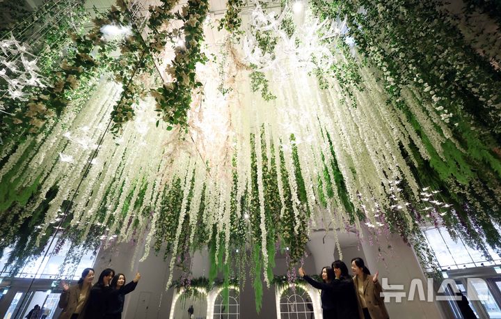 [부산=뉴시스] 하경민 기자 = 6일 부산 해운대구 신세계센텀시티 지하2층 중앙광장에 조성된 '하이퍼 가든'(Hyper Garden)을 찾은 시민들이 기념사진을 찍고 있다. 오는 5월까지 선보이는 하이퍼 가든은 '모네의 정원'을 테마로 수국, 등나무꽃, 델피늄 등의 화사한 꽃과 천장에서부터 내려오는 아치형 식물, 새 모형의 조명 등을 더해 봄 분위기를 연출했다. 2026.03.06. yulnetphoto@newsis.com